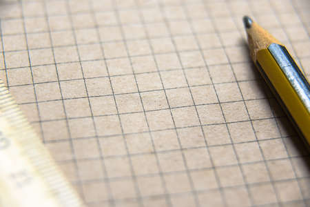 Graph paper of notebook background, blank page of retro sketchbook with old pencil and ruler. Close view of vintage grid sheet, texture squared school notepad or diary, open brown lined note book.の写真素材