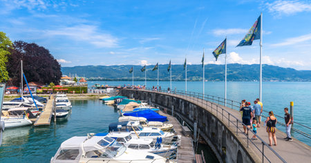 Lindau, Germany - July 19, 2019: Panorama of Lake Constance or Bodensee, people walk next to yachts in harbor. This old town is tourist attraction of Bavaria. Constance landscape in summer.のeditorial素材
