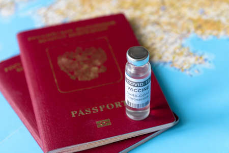Coronavirus, travel and vaccine concept, bottle of COVID-19 vaccine and passports on tourist map. COVID vaccination due to restrictions and lockdown. World tourism hit by corona virus during pandemicの写真素材