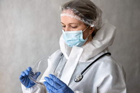 Doctor in personal protective equipment (PPE) from COVID-19, portrait of tired woman physician in medical coverall due to coronavirus, female doctor with suit, mask and glasses. Corona virus concept.の写真素材