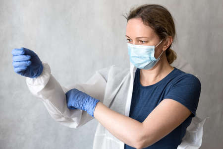 Doctor puts on personal protective equipment (PPE) due to COVID-19, female nurse with medical...