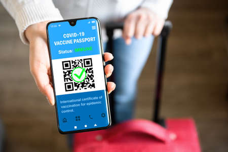 COVID-19 vaccination passport in mobile phone for travel, tourist holds smartphone with health certificate app, digital coronavirus pass. Concept of corona virus, immunity passport and tourism.