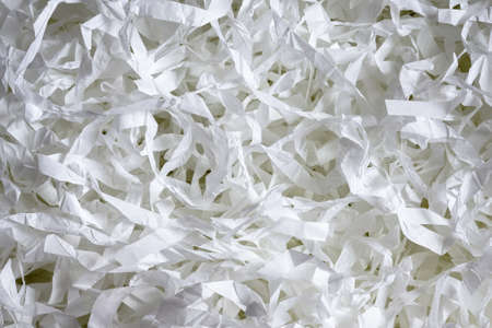 Paper texture background, top view of many white paper strips. Pile of cut paper like confetti for party or box filler for shipping fragile items close-up. Concept of shredding, recycle, waste.の写真素材