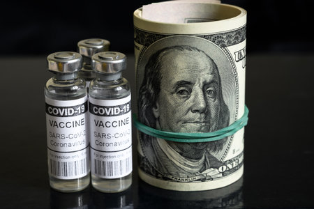 Coronavirus vaccine vials and rolled dollar bills on dark background. COVID-19 vaccine with US...