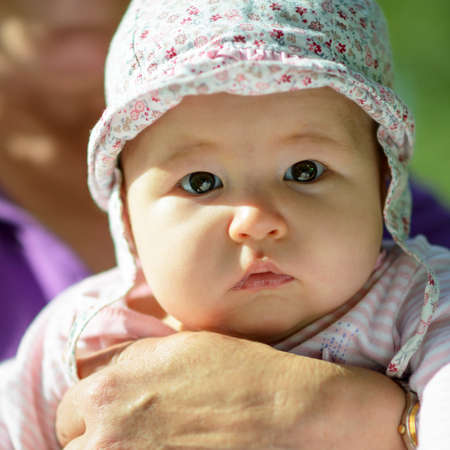 Newborn baby girl on grandmother hands, portrait of infant close-up. Senior woman holds her...