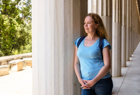 Female tourist visits Stoa of Attalos, Athens, Greece, Europe. Young pretty woman stands by Ancient...