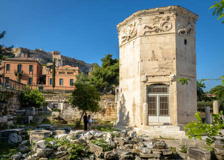 Tower of Winds or Aerides in Roman Agora, Acropolis in distance, Athens, Greece. It is tourist attraction of Athens. View of Ancient Greek ruins in Athens city center. Travel and old history concept.の写真素材
