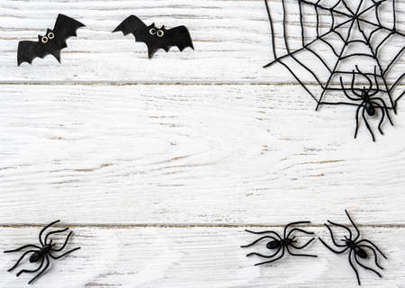 Halloween background with spiders, web and bats, top view. Halloween objects on white wooden table with space for text, flat lay. Minimalist Hallowen decorations. Happy Halloween and horror concept.の写真素材