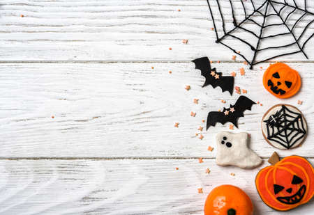 Halloween background with cookies, ghost and bats, top view. Halloween funny objects on white wooden table with space for text, flat lay. Hallowen food and decorations. Happy Helloween concept.の写真素材