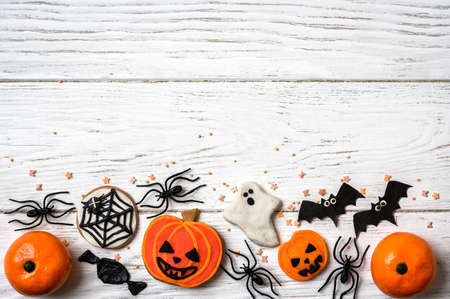 Halloween background with cookies, ghost and bats, top view. Halloween funny objects on white wooden table with space for text, flat lay. Hallowen food and decorations. Happy Helloween concept.の写真素材