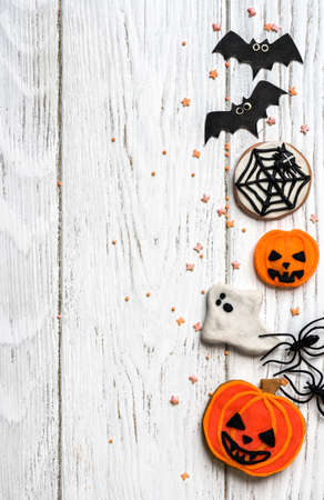 Halloween background with cookies, ghost and bats, top view. Halloween funny objects on white wooden table with space for text, flat lay. Hallowen food and decorations. Happy Helloween concept.の写真素材