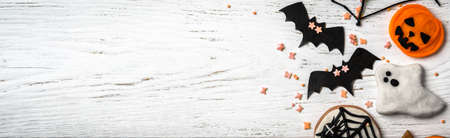 Halloween background with cookies, ghost and bats. Panoramic top view of sweets on white wooden table and space for text on Halloween, flat lay. Hallowen food and decorations. Happy halloween conceptの写真素材