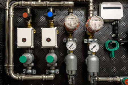 Water pipes, valves and manometers inside house, system with electric pumps and heaters. Metal...