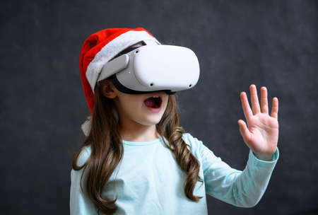 Kid using virtual reality headset, child looking in VR glasses. Young person with futuristic goggles having fun, little girl playing video games simulator. Christmas, New Year and technology concept.の写真素材