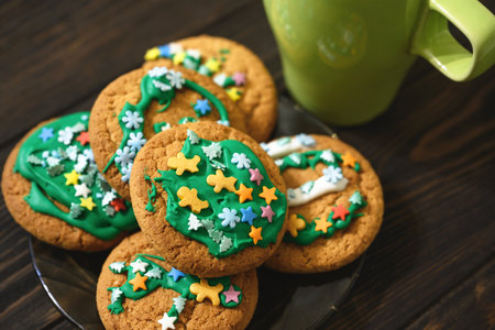 Oatmeal cookies on plate and coffee cup on wooden table, homemade Christmas biscuit decorated sugar...