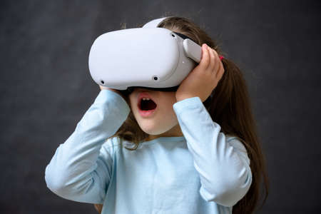 Kid using virtual reality headset, surprised child looking in VR glasses. Young person with...