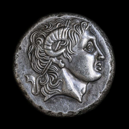 Alexander the Great head on Ancient Greek coin of Lysimachus, 290 BC. Silver tetradrachm, old rare money isolated on black, macro. Concept of Hellenistic Greece, valuable coin and ancient history.の写真素材