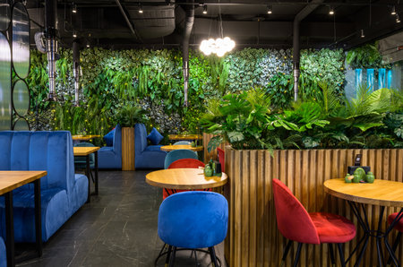 Moscow - Dec 17, 2021: Vertical garden in restaurant interior, landscaping inside modern cafe, cozy eco design indoor. Wall with natural green plants, nature in beautiful contemporary interior.のeditorial素材