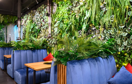 Moscow - Dec 17, 2021: Vertical garden in restaurant interior, wall with natural green plants, landscaping inside modern cafe. Cozy eco design indoor, nature in beautiful contemporary interior.のeditorial素材