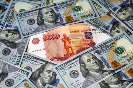 Russian ruble money vs US dollar, ruble banknote between dollar bills. Concept of sanctions, strong currency, confrontation, economy of Russia and USA, exchange rate, inflation, crisis, geopolitics.の写真素材