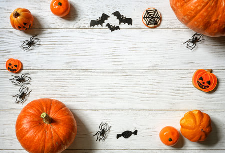 Halloween background, top view. Pumpkins and sweets on white wooden table, flat lay. Frame of Halloween orange food and decorations on wood planks with space. Design, fall, October, treat and trick.の写真素材