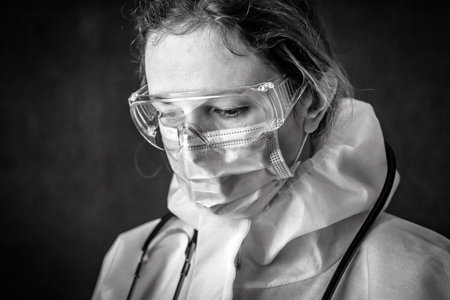 Tired exhausted doctor in personal protective equipment (PPE), nurse wearing medical glasses and face mask, portrait of woman in professional suit due to COVID-19 coronavirus. hospital care concept.の写真素材
