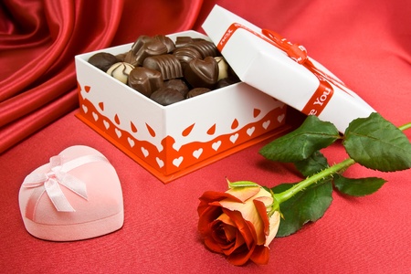 Opened candy box with chocolate and rose on the red background.の写真素材