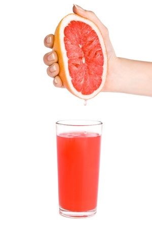 Women`s hand that squeezes grapefruit juice in the glass.の写真素材