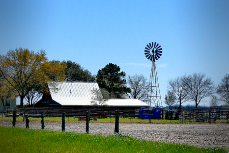 Farm ranch with barn shed and fence with active windmill on a sunny dayの写真素材