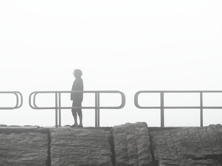 Woman standing on jetty on a foggy dayの写真素材