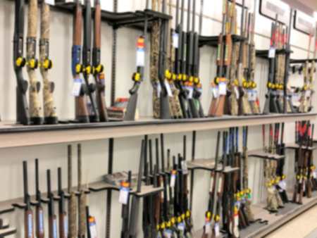 Blurred photo of gun rifle display for sale in sporting goods store shopの写真素材