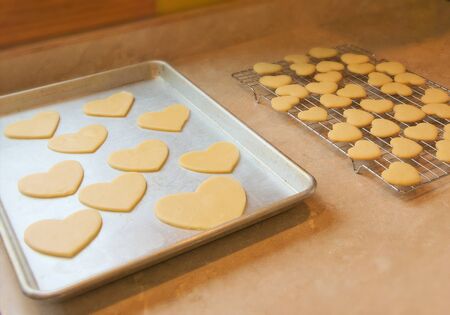 Grandmothers tasty homemade Valentine sugar cookies on baking sheet and cooling rack. Delicious...