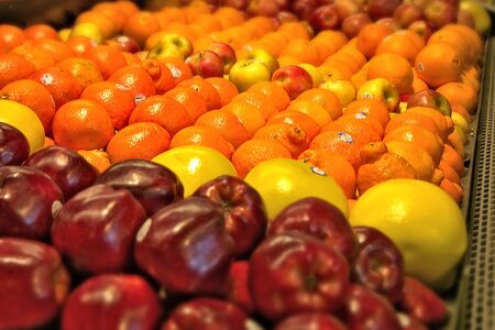 Fresh fruits that are for sale at a market. Oranges apples and grapefruit with selective focus.