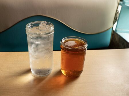 Two cold beverages with condensation on glass sitting on a table in a retro cafe with natural light....