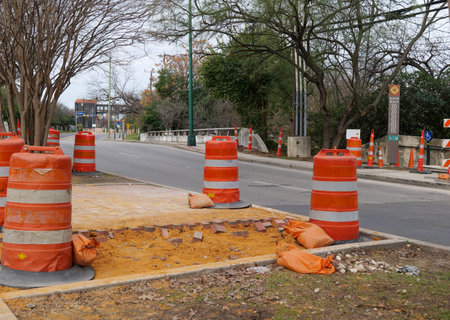 SAN ANTONIO, TX - 25 JAN 2020: Orange warning barrels at a road construction site with cars driving by on the street.のeditorial素材