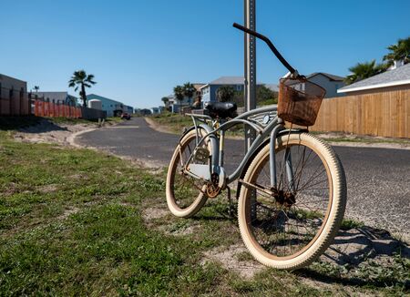 Old rusty bicycle leaning against a street sign post on a sunny day.