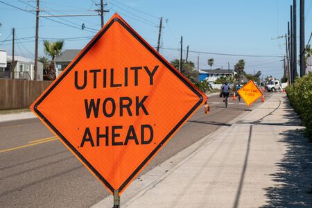 Utility Work Ahead sign on sidewalk next to street warns traffic about work project zone in...