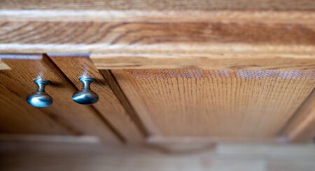 Oak cabinet doors with two brushed metal knobs. Narrow depth of field focus.の写真素材