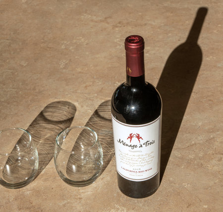 BEMIDJI, MN - 15 MAY 2020: Bottle of uncorked red wine on a table top alongside two stemless wine glasses.のeditorial素材