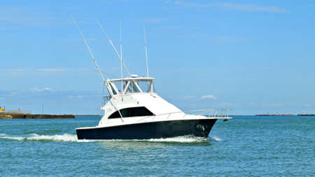 Broadside view of a beautiful white and black fishing yacht boat sails left to right on the calm...