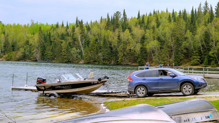 CLEARWATER CO, MN - 23 MAY 2020: Fishing boat with outboard motor on a trailer is pulled out of the water by an automobile at a Minnesota lake.のeditorial素材