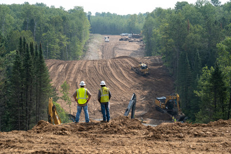 CASS CO, MN - 6 AUG 2021: Enbridge Line 3 Oil Pipeline Construction Site in Minnesota forest with excavators and bulldozers covering the installed pipe. Foreground is intentionally out of focus.のeditorial素材