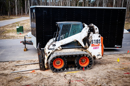 CROW WING CO, MN - 5 MAY 2022: Bobcat with forklift and black trailer.