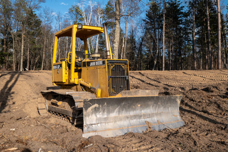 CROW WING CO, MN - 10 MAY 2023: Older John Deere Bulldozer with front blade and hydraulics power, parked on a new home construction building site plot of land.のeditorial素材