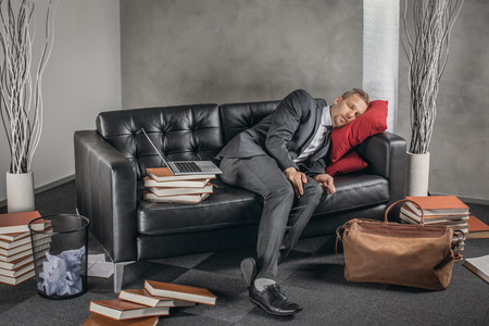 Tired businessman sleeping on the couchの写真素材