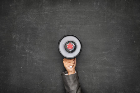 Businessman hand holding megaphone on front of vintage full frame black blank blackboard no frameの写真素材