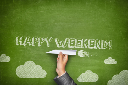Happy weekend concept on green blackboard with businessman hand holding paper planeの写真素材