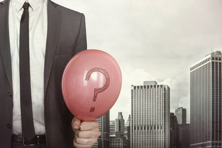 Businessman holding balloon in hand in suit on cityscape backgroundの写真素材