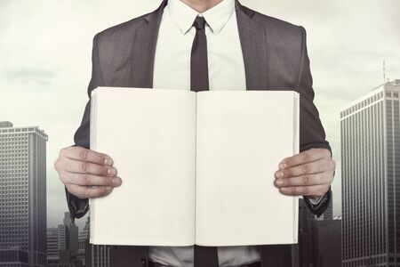 Businessman holding empty book sheet on cityscape backgroundの写真素材