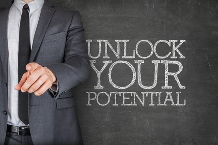 Unlock your potential on blackboard with businessman finger pointingの写真素材